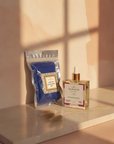 Royal African Exfoliating Net and Unscented Dry Body Oil on a marble slab in soft window shadow