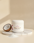 Coconut Cloud Whipped Sugar Scrub jar on a marble tray with a halved coconut and a pile of white sugar