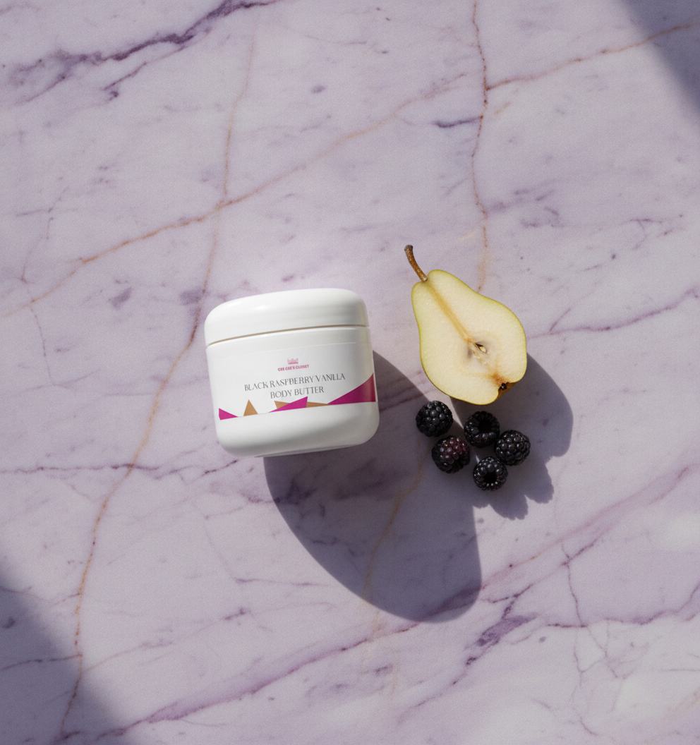 Overhead flat lay of Black Raspberry Vanilla Body Butter with halved pear and blackberries on lilac marble