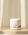 Coconut Cloud Whipped Body Butter jar on travertine in warm sunlight by a sheer curtain
