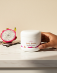 Hand holding a Dragonfruit Vanilla Whipped Body Butter jar with dragonfruit and vanilla